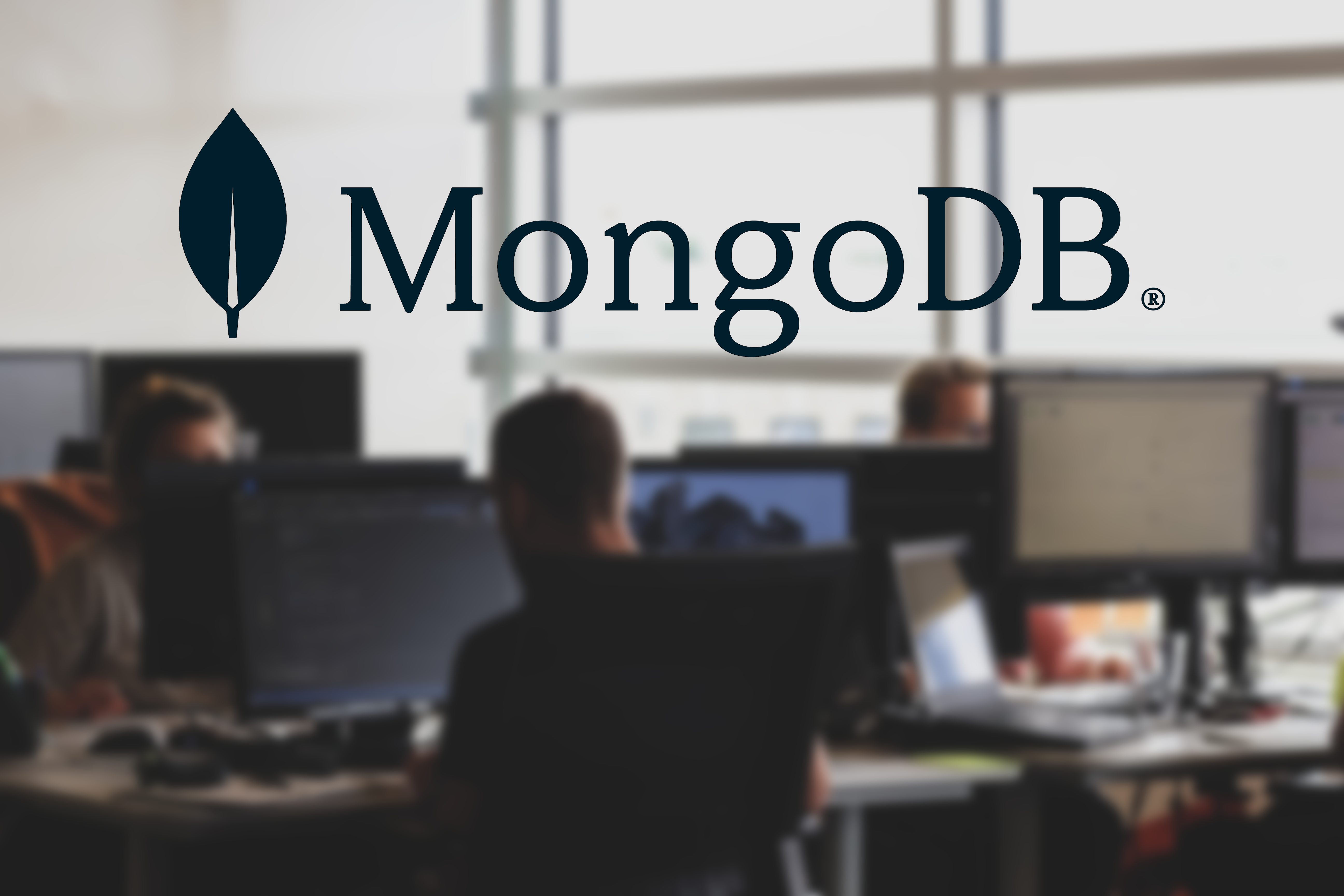 Developers working on computers with MongoDB logo in the foreground